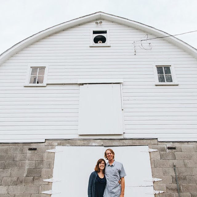 Ali and Scotty Yahnke stand in front of a white barn at their homestead in Omaha, Nebraska, 2017