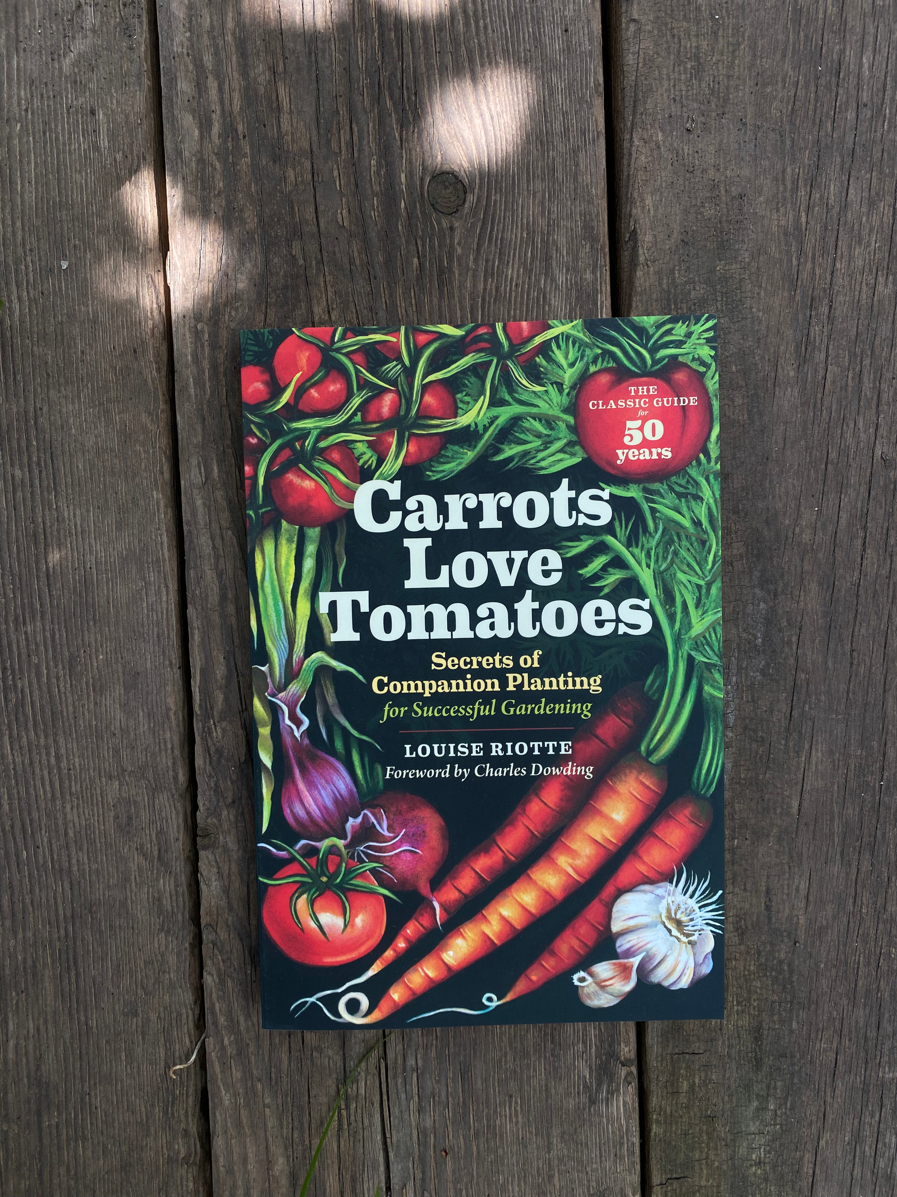 Book titled 'Carrots Love Tomatoes' on a wooden surface