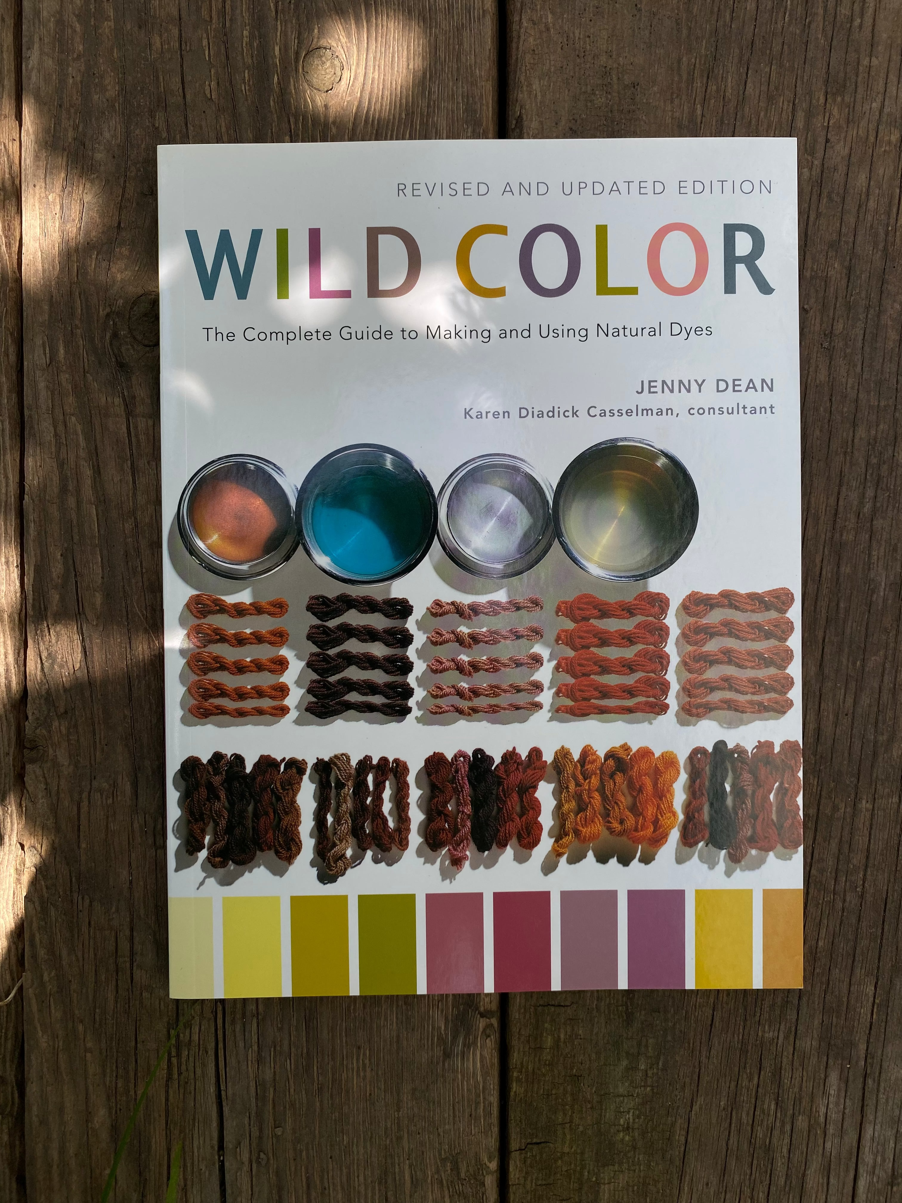 Open book with a floral illustration and color swatches on a wooden surface