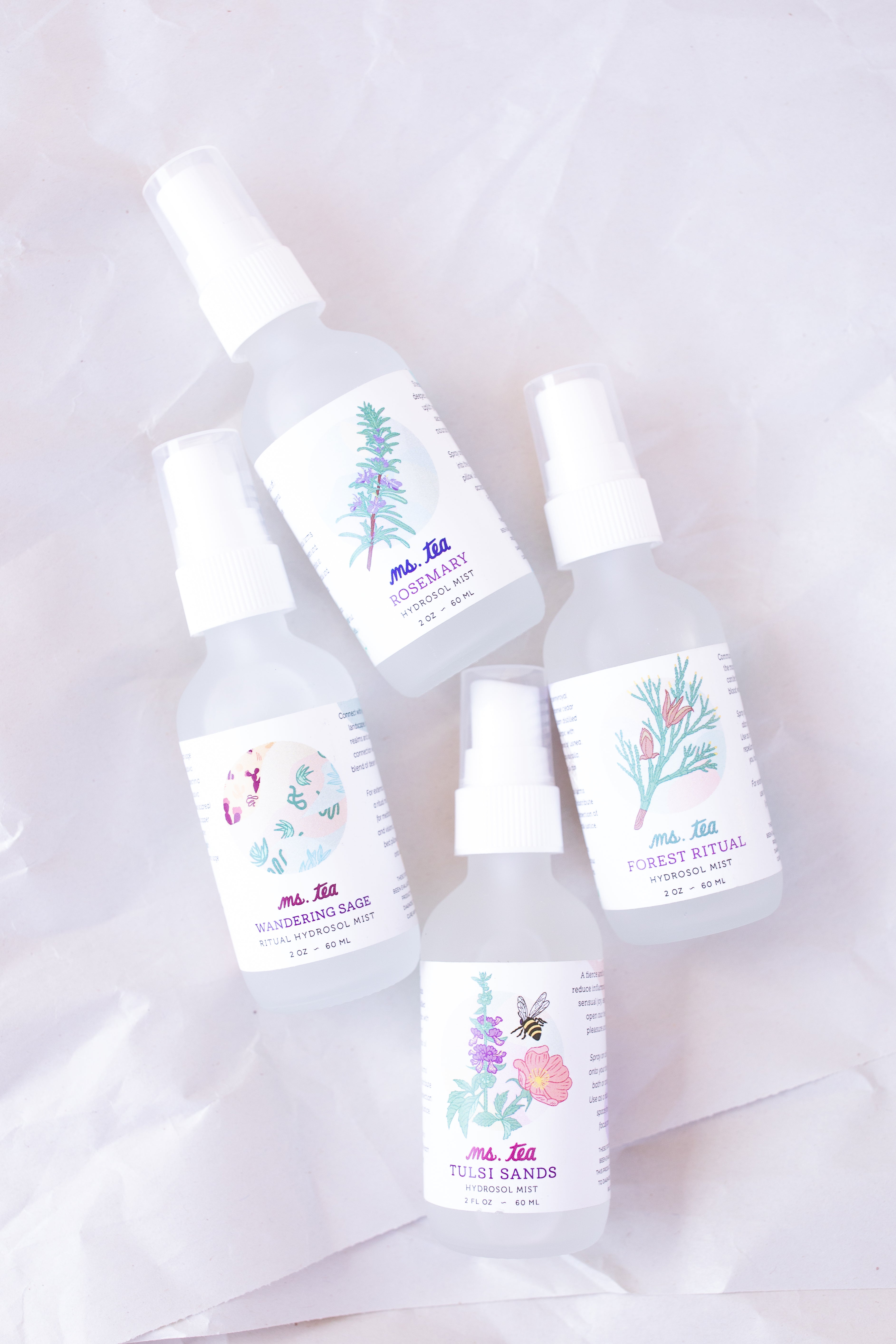 Steam-distilled herbal hydrosol spray bottles on an aethereal background