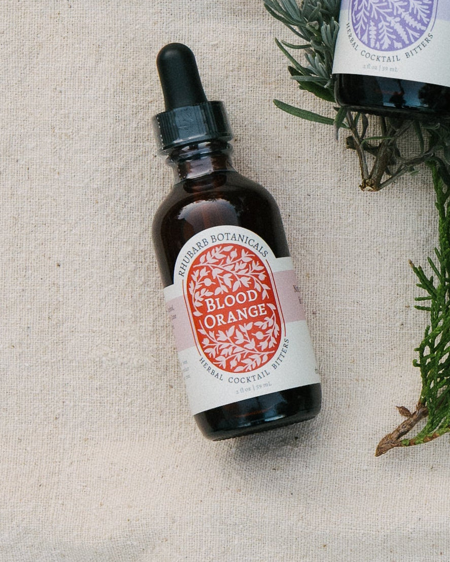 Bitters bottle with labels on a wooden surface with greenery